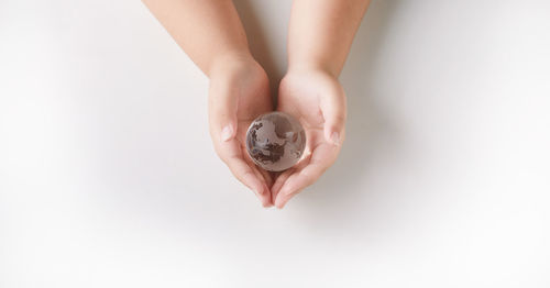 Close-up of woman holding hands over white background