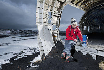 Woman cooking meal on camping stove at famous plane wreck in iceland
