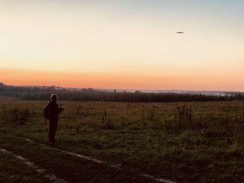 Man standing on field against sky during sunset