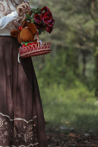 Midsection of woman holding flower and doll on basket