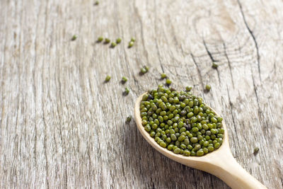 Close-up of green lentils in wooden spoon on table