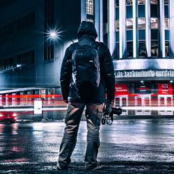 Rear view of man with umbrella on street in rainy season