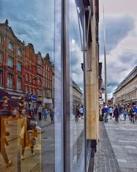 People walking on street in city against sky