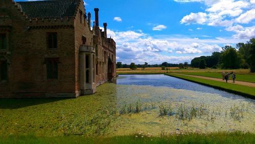 Scenic view of field by buildings against sky