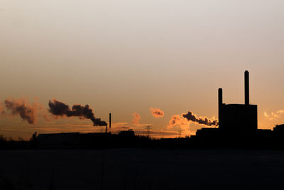 Smoke emitting from factory against sky during sunset