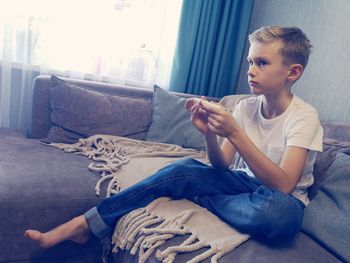 Boy sitting on sofa at home