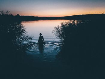 Silhouette man in lake against sky