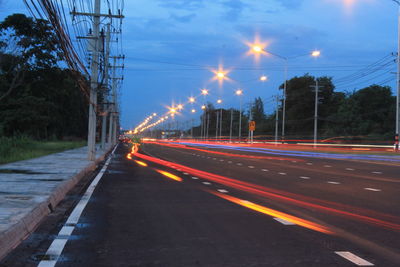 Light trails on road against sky at night