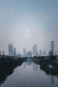 Buildings by river against sky in city