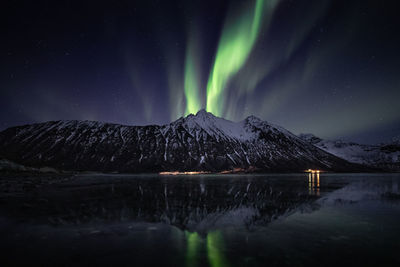 Scenic view of lake by mountain against sky at night