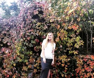 Portrait of young woman standing by plants