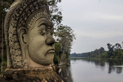 Close-up of statue by lake against sky