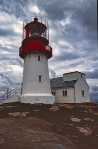 Low angle view of lighthouse by building against sky