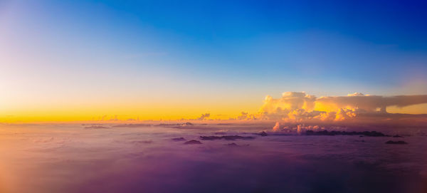 Smoke emitting from volcanic landscape against sky during sunset