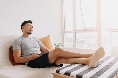 Young woman using laptop while sitting on bed at home