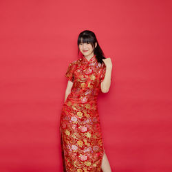 Portrait of smiling young woman against red background