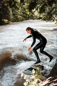 Side view of man splashing water in river