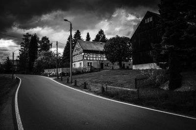 Road by buildings against sky in city