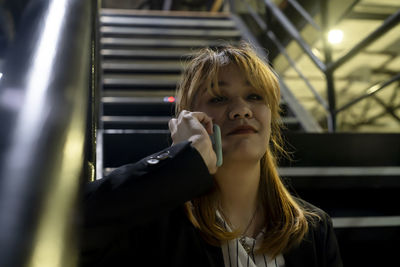 Portrait of young woman talking over smart phone on steps