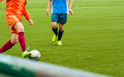 Low section of people playing soccer on field