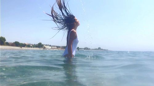 Woman in sea against clear sky