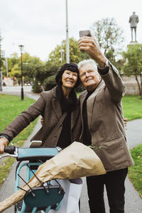 Senior couple taking selfie with electric bicycle through smart phone in park during weekend