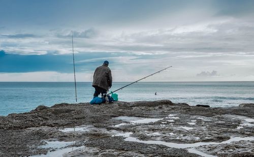 Man with fishing rod at coastline