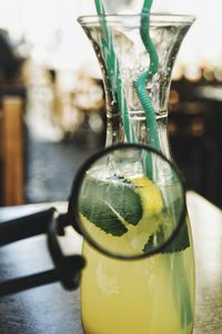 Close-up of magnifying glass against drink on table