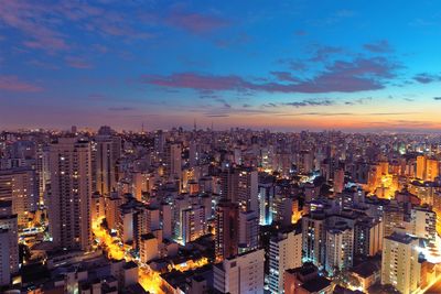 Aerial view of illuminated buildings in city against sky during sunset