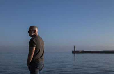 Adult man against sea and sky with lighthouse in background. almeria, spain