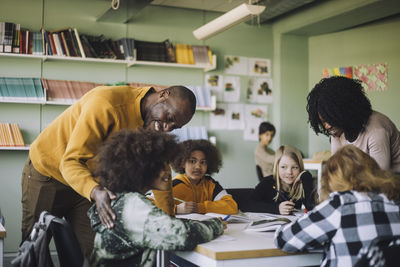 Teachers assisting students while studying in classroom at school