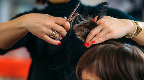 Hairdresser's hands with scissors cutting boys hair in hair salon