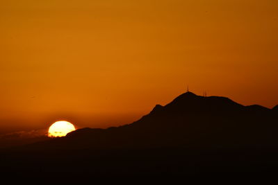 Scenic view of silhouette mountains against orange sky