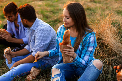 Friends eating food sitting at park