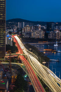 Aerial view of light trails on road by buildings