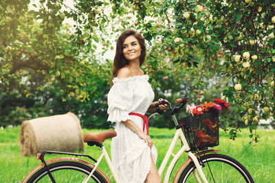 Smiling woman with bicycle at apple orchard