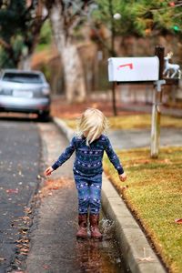 Rear view of woman with umbrella on road