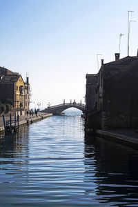 Bridge over river by buildings against sky