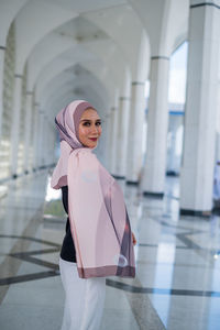 Portrait of woman standing in corridor of building