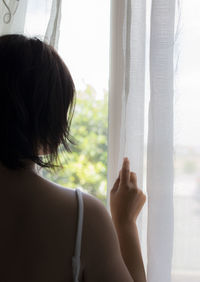 Rear view of woman looking through window