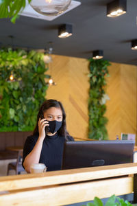 Young woman using phone in restaurant