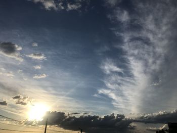 Low angle view of sunlight streaming through clouds