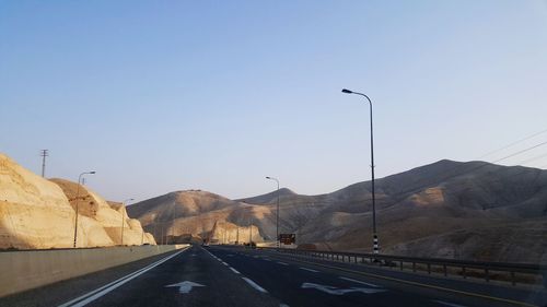 Street by mountain against clear sky