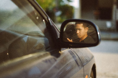 Portrait of young man looking through car window