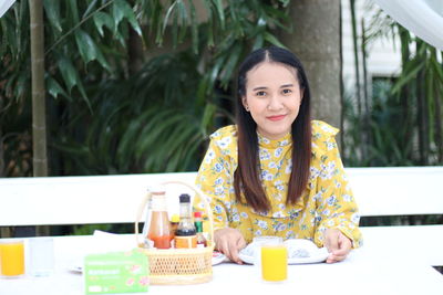 Portrait of a smiling young woman sitting on table