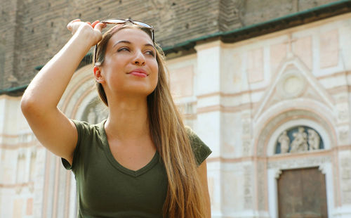 Portrait of young woman standing against wall
