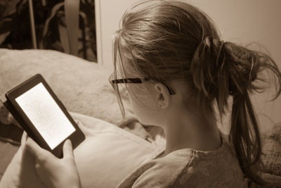 Close-up of woman using digital tablet while sitting on bed