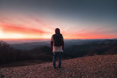 Woman standing on snow covered landscape at sunset