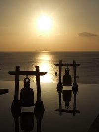 Rear view of silhouette man standing by sea against sky during sunset