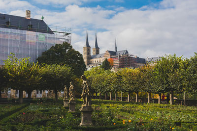 Trees in city against cloudy sky